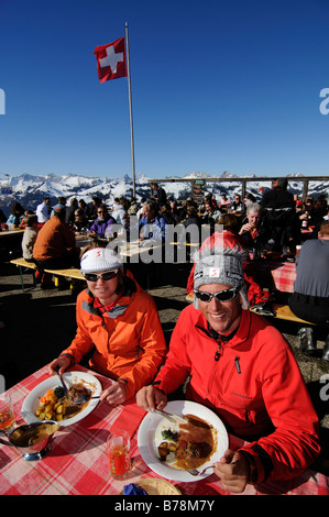 I villeggianti gustando un pasto nel Cafe Horneggli, Schoenried, regione sciistica di Gstaad, Alpi occidentali, Oberland bernese, Switzerla Foto Stock