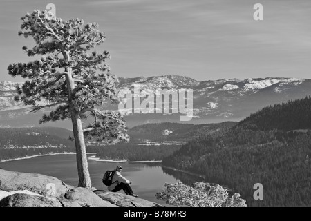 Un uomo seduto da un albero sopra Donner del lago in un giorno di neve in California Foto Stock