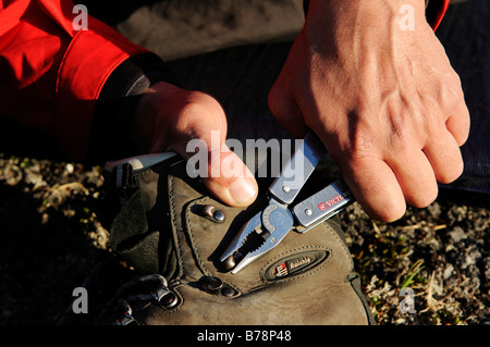 Trekker riparazioni il suo alpinismo boot con Leatherman tool, Ikasartivaq-Fjord, East-Greenland, Groenlandia Foto Stock