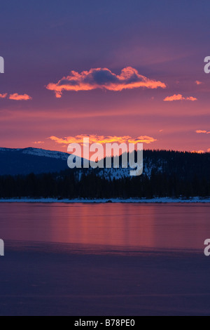 Rosa alpenglow nuvole a sunrise riflettendo su ghiaccio sul lago Donner in California Foto Stock