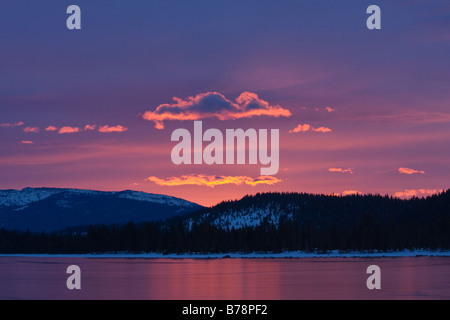 Rosa alpenglow nuvole a sunrise riflettendo su ghiaccio sul lago Donner in California Foto Stock