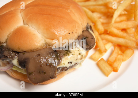 Un fungo e formaggio beefburger,servito con patate fritte. Un tipico fast-food pasto Foto Stock