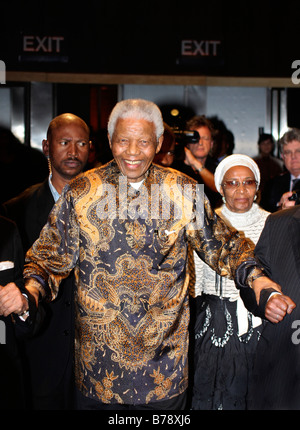 Sorridendo Nelson Mandela di entrare in una stanza con il suo entourage a George Bizos fund raising in funzione di Johannesburg Foto Stock