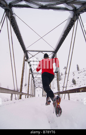 Un uomo che corre attraverso un ponte tressel su un giorno nevoso vicino Truckee in California Foto Stock