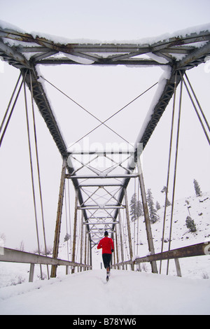 Un uomo che corre attraverso un ponte tressel su un giorno nevoso vicino Truckee in California Foto Stock