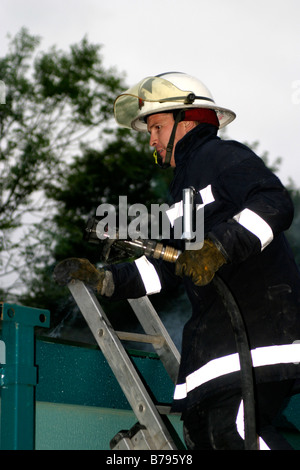 Fire Fighter su una scala Foto Stock