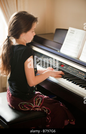 Ragazza giovane la riproduzione di una tastiera per pianoforte elettronico Foto Stock