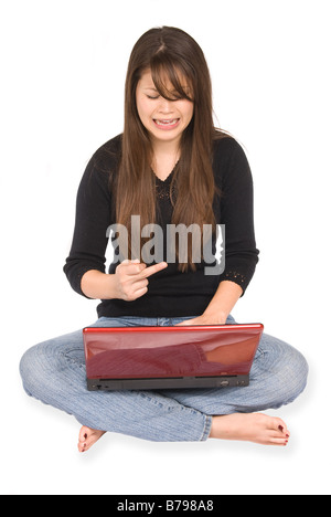 Una giovane donna ottiene frustrato con il suo computer portatile e segnali il suo dito medio in frustrazione Foto Stock