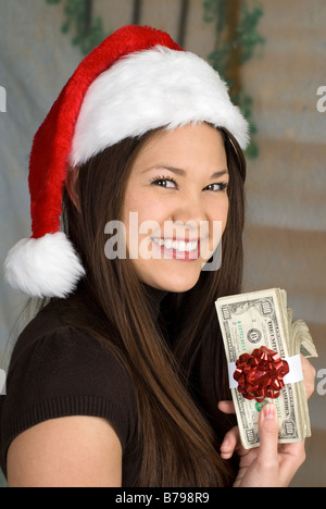 Una donna visualizza il suo regalo di Natale sotto forma di una pila di banconote da cento dollari Foto Stock