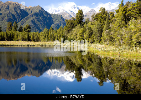 Lago Matheson sull'Isola del Sud della nuova Zelanda, Mt Tasman e Aoraki Mt Cooki in lontananza, vette innevate, sole autunnale Foto Stock