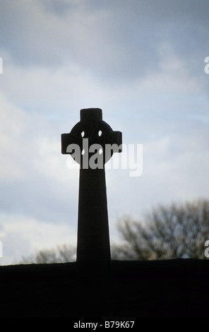 Un memoriale di guerra sotto forma di una croce celtica sta solo sotto il cielo plumbeo nel cimitero di Durham Cathedral, Inghilterra. Foto Stock
