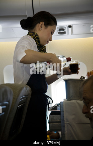 Equipaggio di cabina / hostess di aria, con un carrello della spesa, infonde spirito (probabilmente vodka in coke) per un passeggero durante un volo (45) Foto Stock