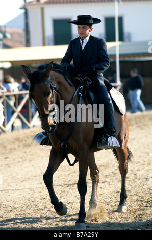 Un ragazzo vestito nel tradizionale abito equestre in sella ad un cavallo lusitano durante il Golegã horse festival in Portogallo Foto Stock