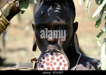 Ritratto di una giovane donna, che indossa una argilla punteggiata labbro disco e dischi di argilla in lei i lobi delle orecchie, Mursi, Murzu, vicino Jinka, Etiopia, un Foto Stock