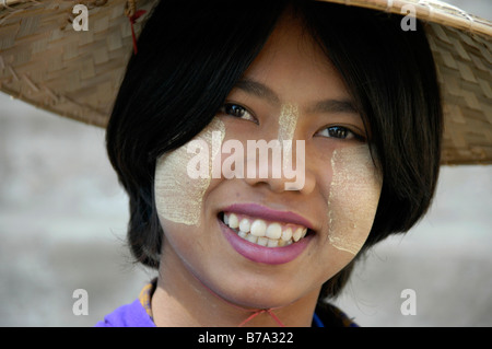 Sorridente giovane donna indossa tanaka sul suo viso e una paglia di riso hat sulla sua testa, Mingun, vicino a Mandalay, birmania, myanmar, Southea Foto Stock