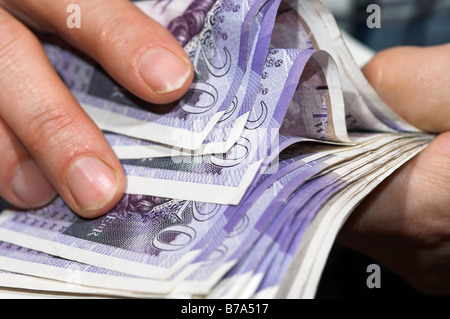 Mano che tiene un fascio della sterlina inglese banconote Foto Stock