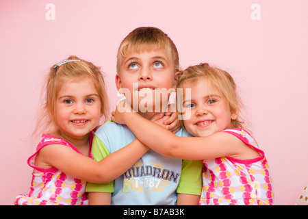 3 anni di due gemelle che abbraccia un anno sette old boy Foto Stock
