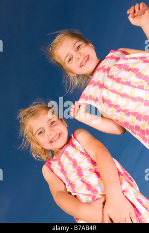 3 anno vecchio sorridente twin ragazze contro il cielo blu Foto Stock