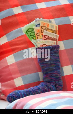 Calza di risparmio su un letto riempito con le banconote in euro, crisi finanziaria ansia Foto Stock