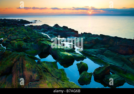 Seascape vista sul fiume Clyde al tramonto su uno sperone roccioso a bassa marea Foto Stock