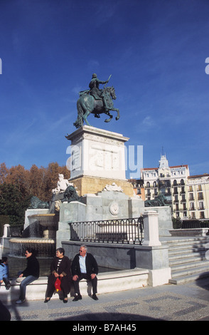 Turisti seduti sul muro intorno alla piscina di fronte alla statua del re Filippo IV, Plaza de Oriente, Madrid, Spagna Foto Stock