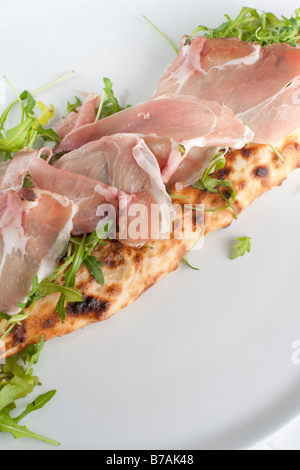 Calzone con spek e rucola. La pizza italiana con prosciutto affumicato. La messa a fuoco del prosciutto. Foto Stock