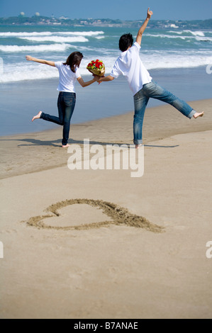 Coppia giovane in piedi presso la spiaggia che allietava Foto Stock