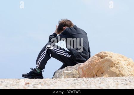 Ragazzo seduto sulle rocce da coste Foto Stock