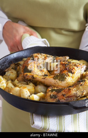 Close-up di arrosto di cosce di pollo arrosto le cipolle e le patate in una padella in ghisa Foto Stock