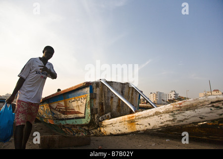 Colorfully dipinto barche da pesca la linea della spiaggia a questo mercato del pesce di Dakar in Senegal. Foto Stock