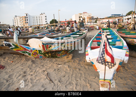 Colorfully dipinto barche da pesca la linea della spiaggia a questo mercato del pesce di Dakar in Senegal. Foto Stock