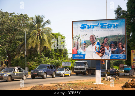 Una pubblicità tramite Affissioni Sur Eau sorge accanto ad una strada trafficata attraverso la Guinea la capitale Conakry. Foto Stock
