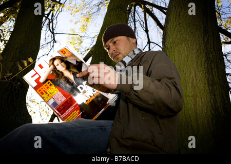 Un uomo che legge un FHM magazine Foto Stock