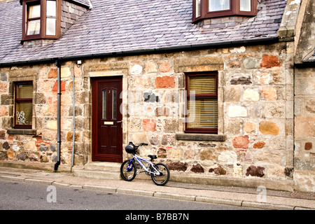 Biciclette per bambini dal portello anteriore di una casa di pietra in Scozia Foto Stock