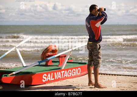 Bagnino di salvataggio del peering guardando il mare con il binocolo Foto Stock