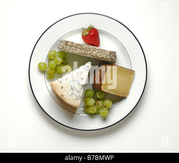 Tre diversi blocchi di formaggio con uva verde e una fragola su una rotonda bianca piastra cena Foto Stock