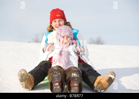 13 e 9 anno Olds scorrere giù per la collina, Winnipeg, Canada Foto Stock