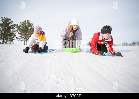 3 bambini (14, 13 e 9 anni) scorrendo giù per la collina, Winnipeg, Canada Foto Stock