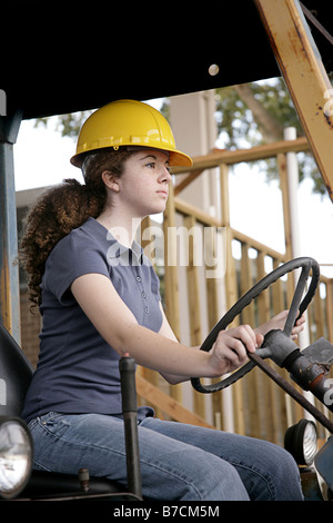 Una femmina di lavoratore edile la guida di apparecchiature pesanti vista verticale Foto Stock