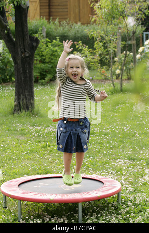 Piccola ragazza bionda saltando su un trampolino, Germania Foto Stock