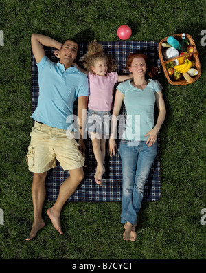 Una famiglia che giace su una coperta sull'erba Foto Stock