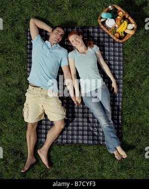 Una giovane coppia giacendo su una coperta con un cesto Foto Stock
