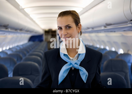 Un assistente di volo in piedi nella cabina di un aereo Foto Stock