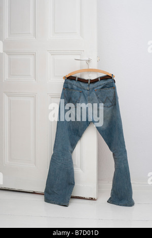 Un paio di jeans appeso a una maniglia di porta Foto Stock