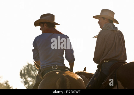 Vista posteriore di due cowboy a cavallo Foto Stock