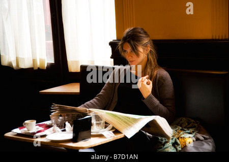 Donna che legge il giornale in un bar Foto Stock