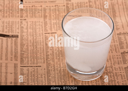 Due solubili di paracetamolo aspirina compresse in un bicchiere di acqua su una copia del Financial Times Foto Stock