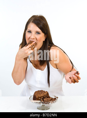 Attraente giovane donna messily mangiare una fetta di torta al cioccolato. Foto Stock
