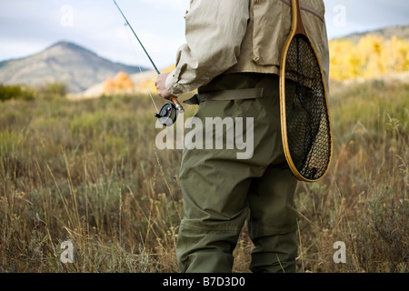 Sezione mediana di un uomo con una canna da mosca e una rete da pesca Foto Stock