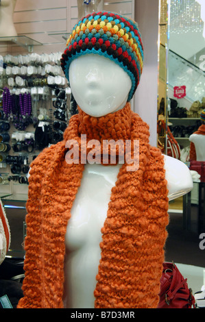 Un corpo superiore shop manichino visualizzando un foulard arancione e colorato berretto lavorato a maglia. Foto Stock